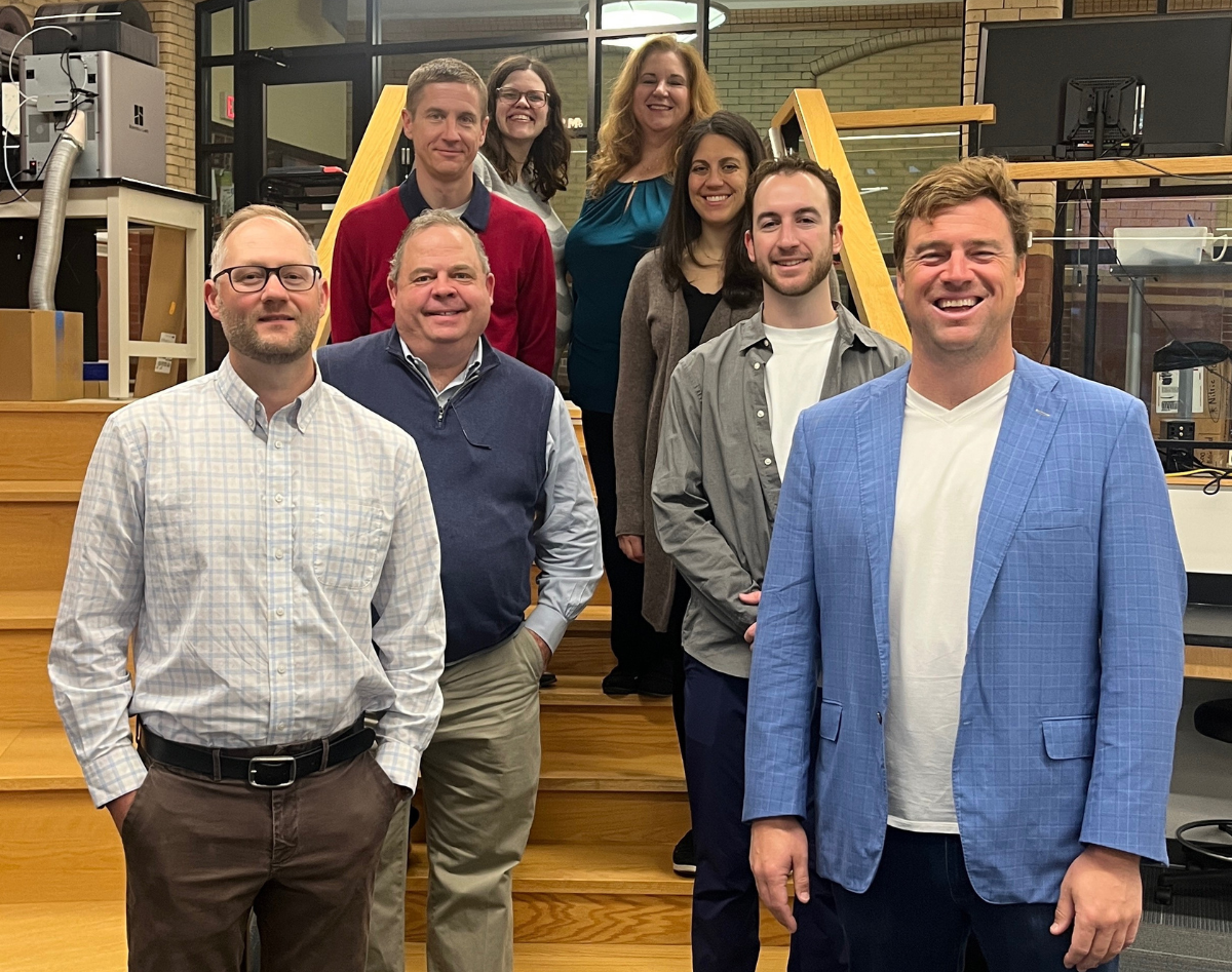7 people standing in building with stairs behind them