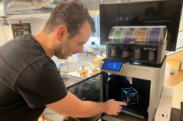 Jared holding a crystal model as it is completed in 3d printer