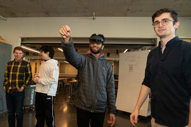 Student wearing AR headset with three other students watching