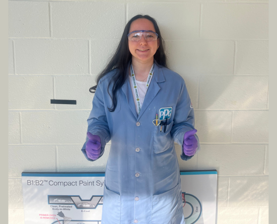 Student wearing lab coat and giving thumbs up