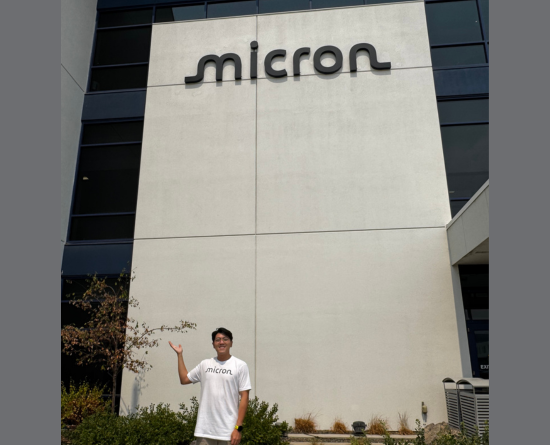 Person standing next to Micron sign