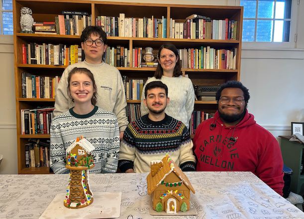 Group photo of members posed with gingerbread houses